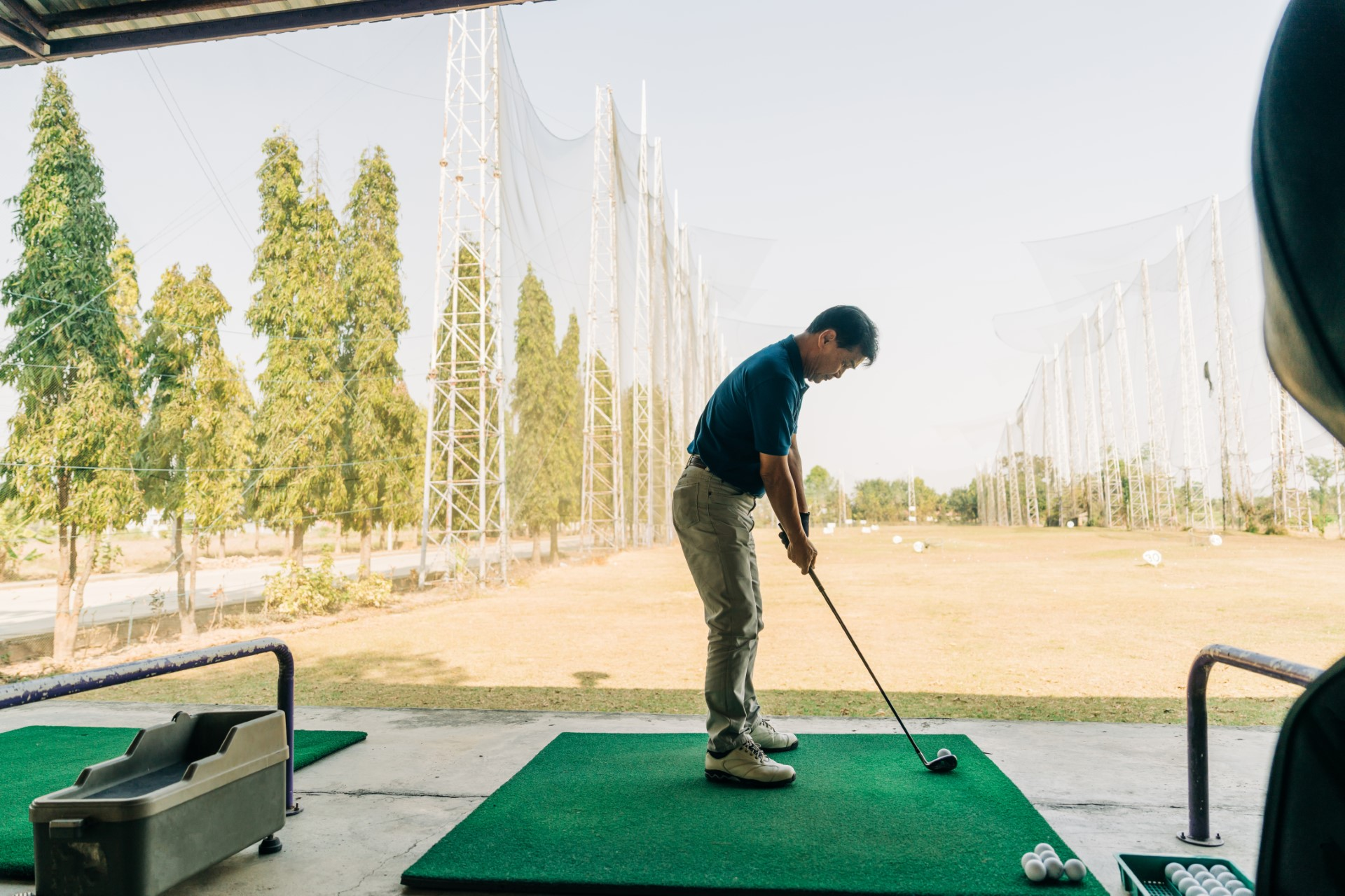 A golfer in a blue shirt practicing his swing at the driving range, refining technique and precision for better performance.